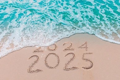 Image of waves erasing 2024 and showing 2025 written into the sand of a beach, symbolising the journey from 2024 to 2025.